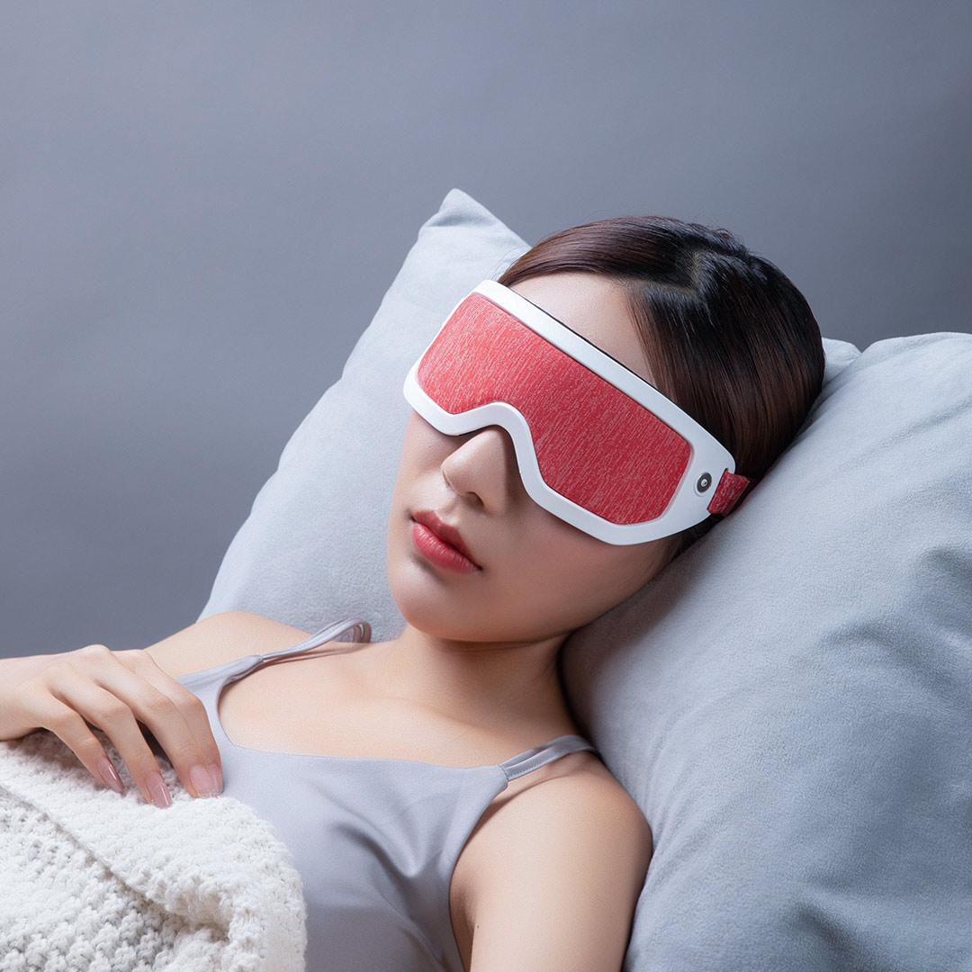F30 Graphene Heated Sleep Eye Mask: woman resting on a pillow with the red mask.