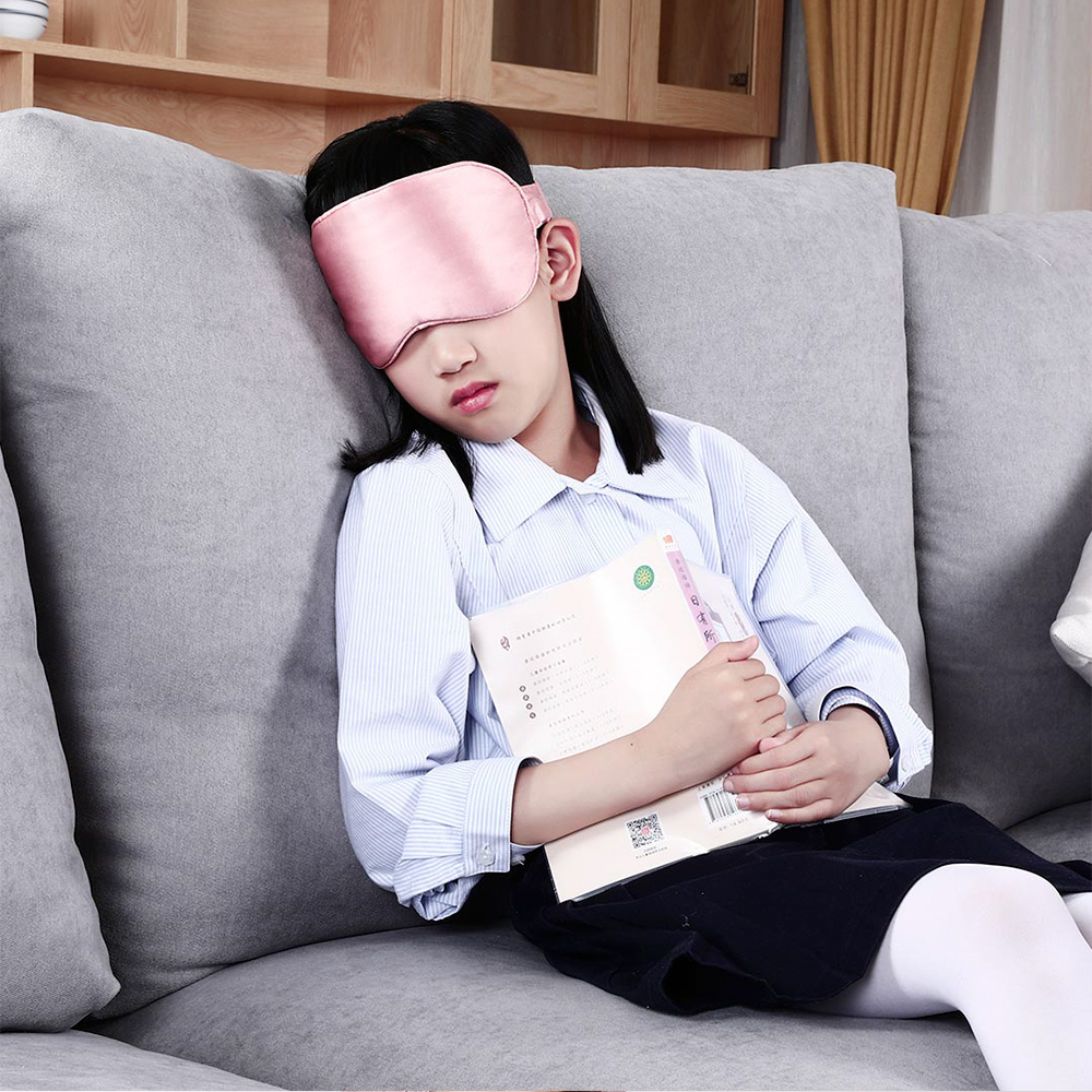 E10 Graphene Heated Silk Eye Mask: woman resting on a sofa with the pink mask.