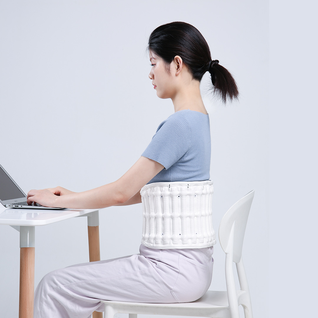 D30 Graphene Heated Airbag Lumbar Support Belt: woman working at a laptop while wearing the belt.