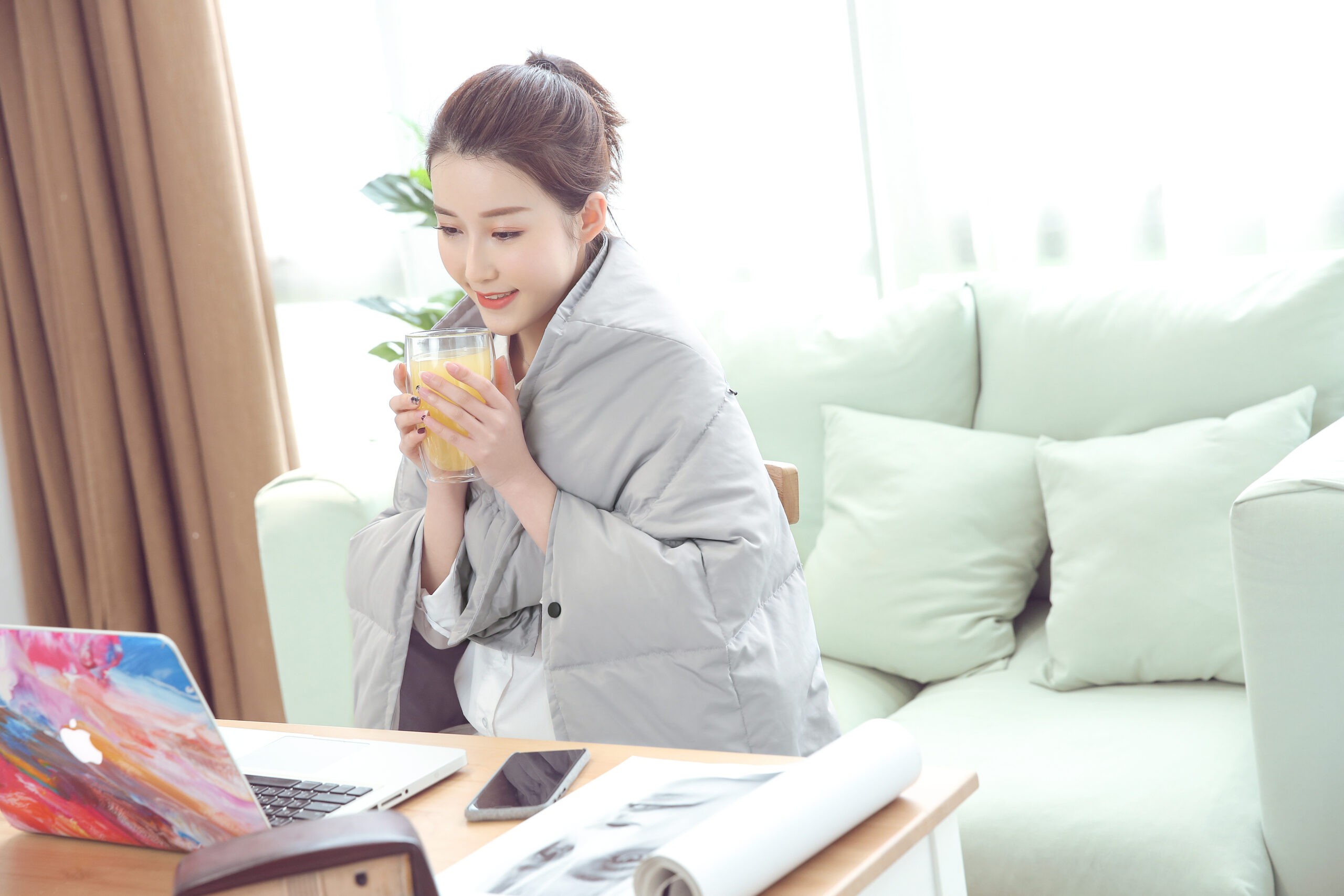 B20 Graphene Heated Down Blanket: woman wrapped in the blanket beside a laptop.