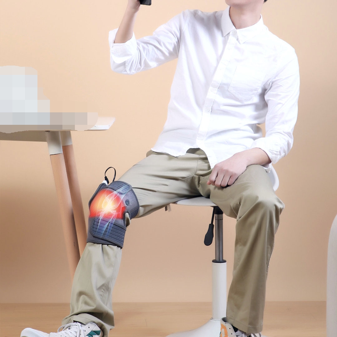 K30 Graphene Heated Knee Pad: man wearing the pad at a desk.