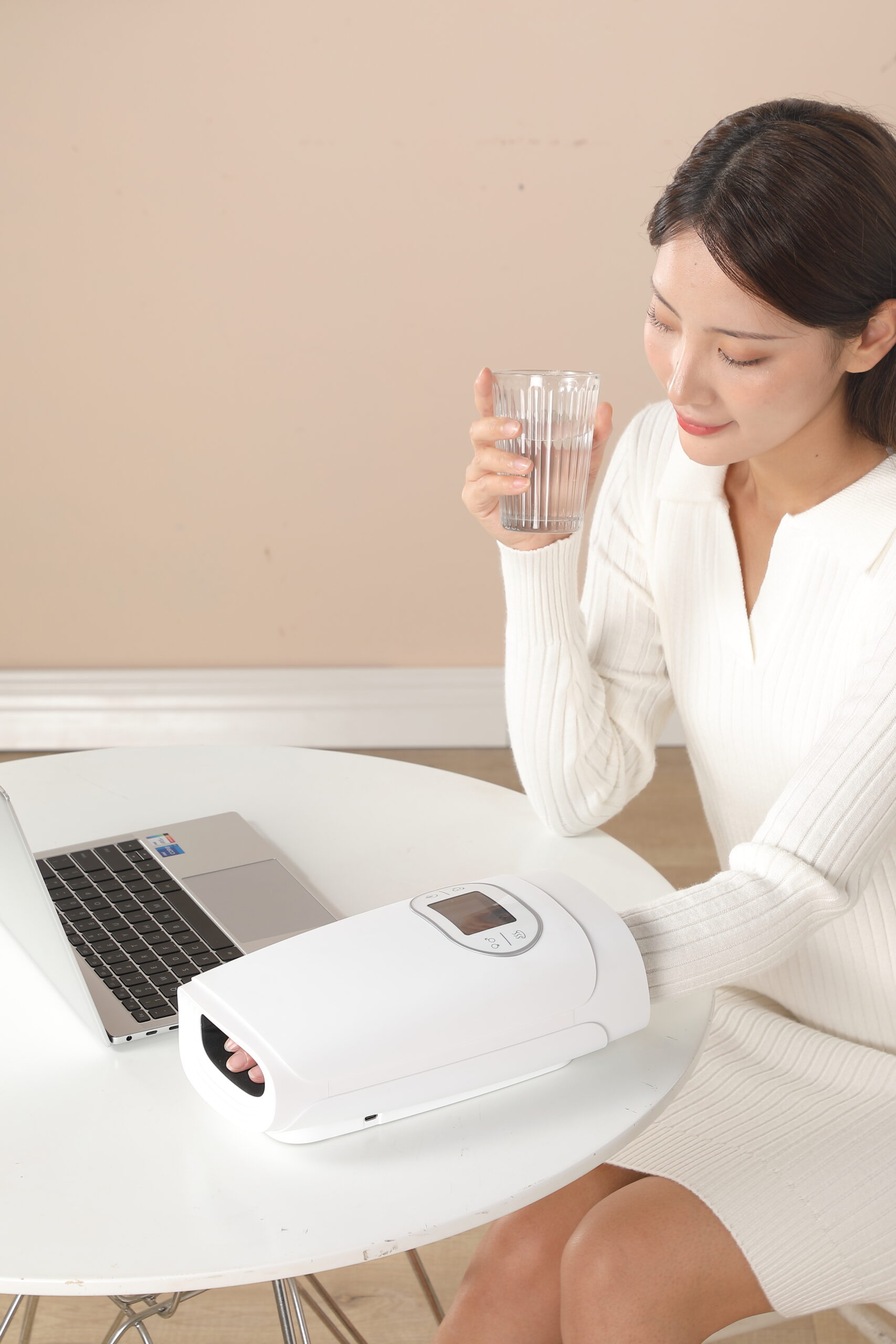Hand Massager: woman using the massager beside a laptop.