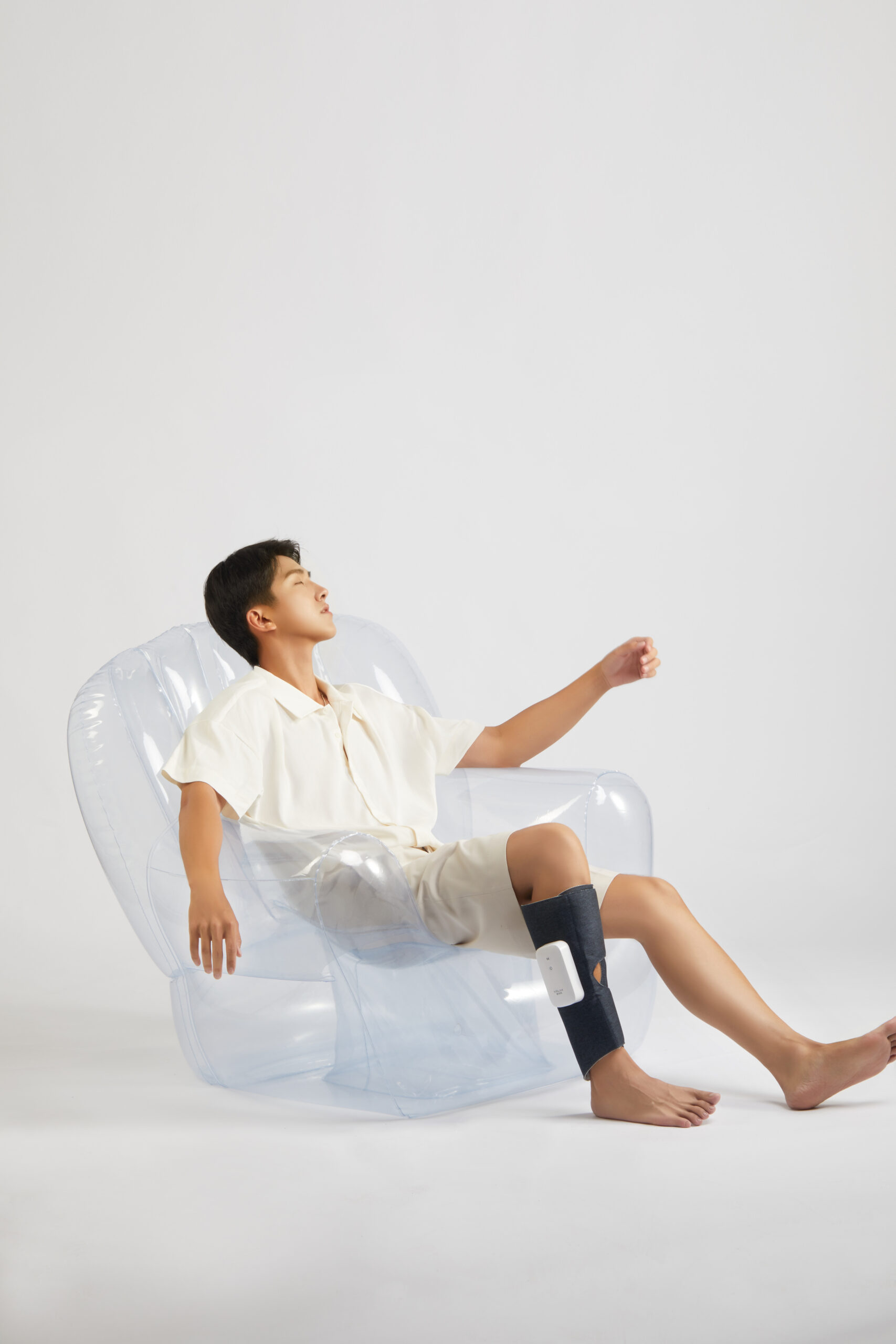 Graphene Leg Massager: man reclining in a clear chair with a calf wrap.