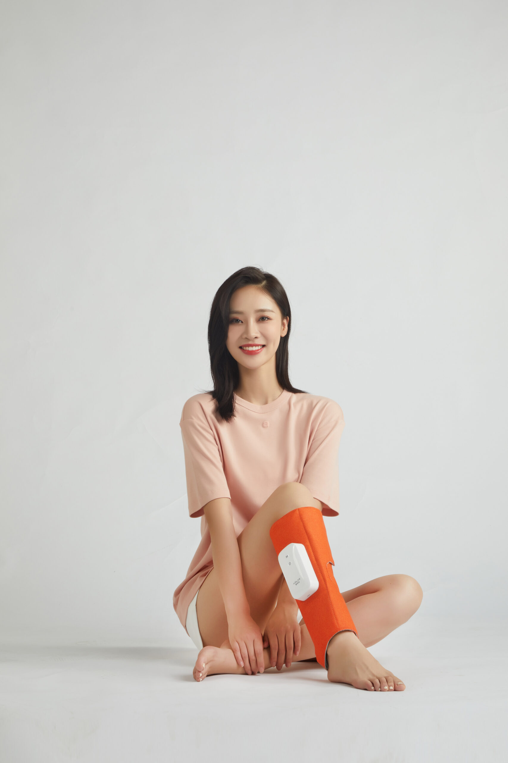 Graphene Leg Massager: woman sitting cross-legged with a calf wrap.