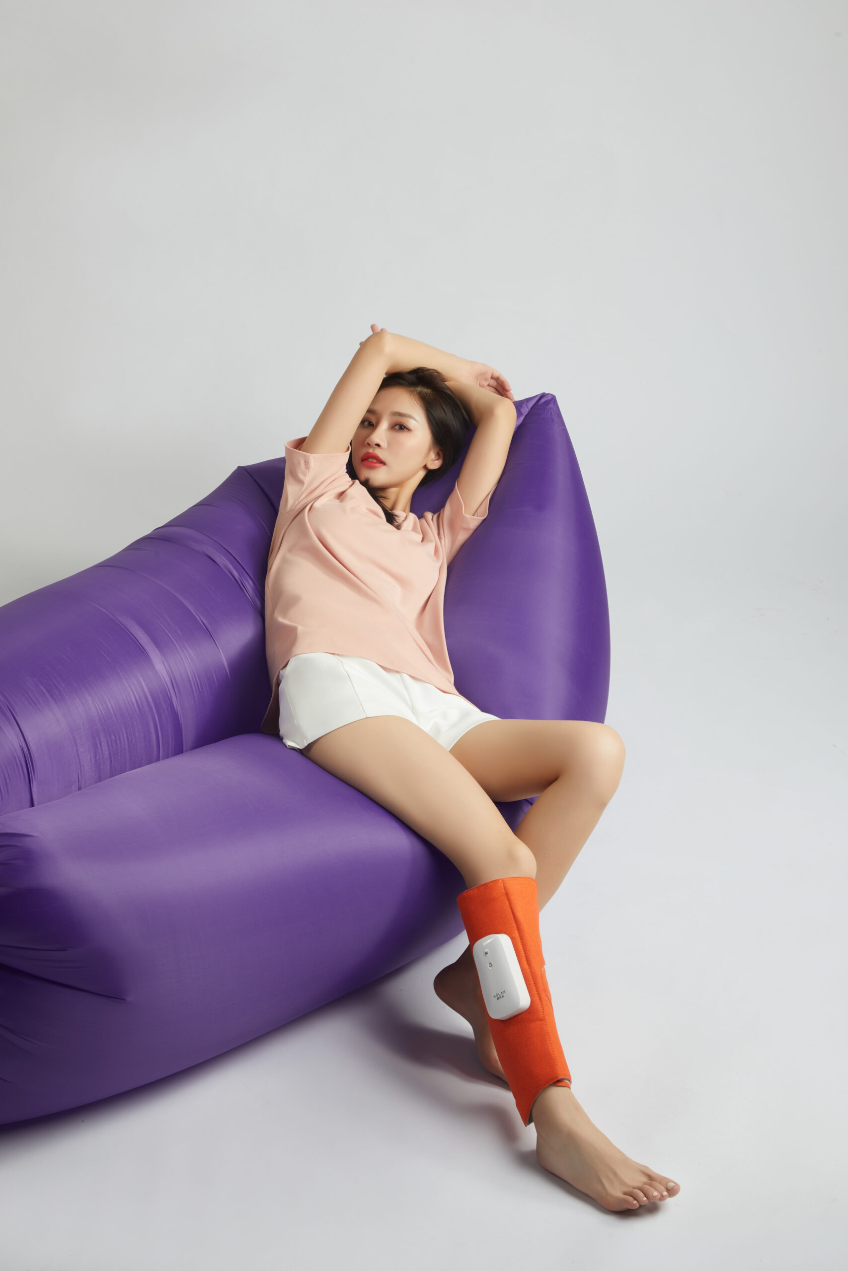 Graphene Leg Massager: woman reclining on a sofa with a calf wrap.
