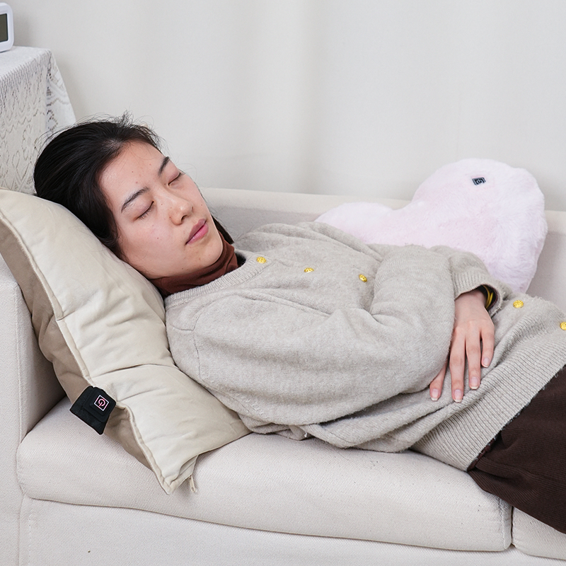 Woman reclining with a gray heart-shaped heated cushion
