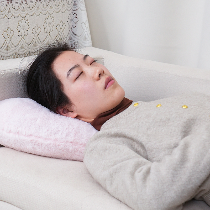 Woman using a gray heart-shaped heated cushion