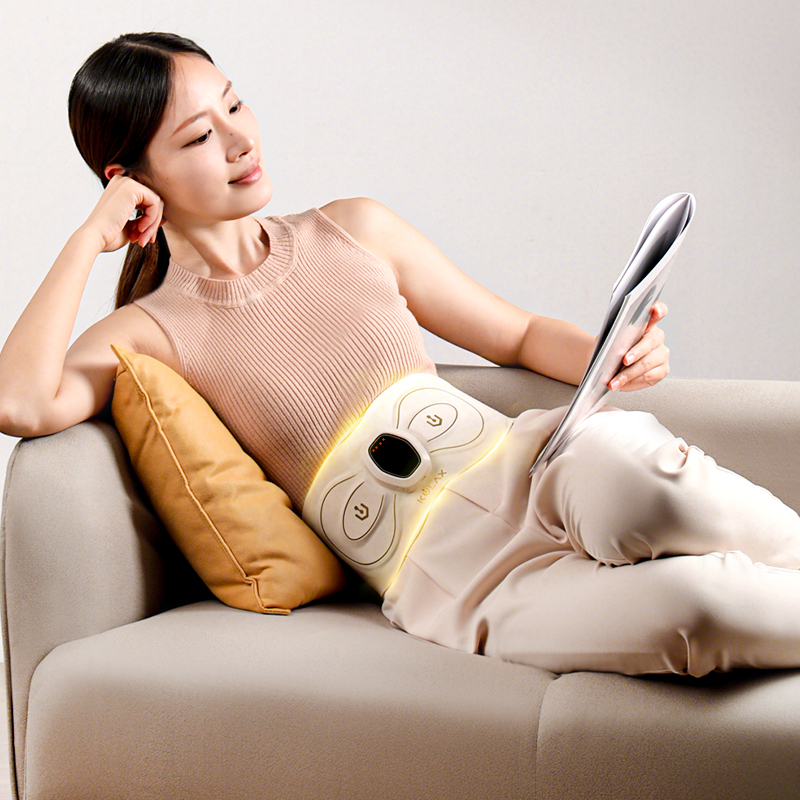 EMS Abdominal & Waist Trainer: woman wearing the belt while reading on a sofa.