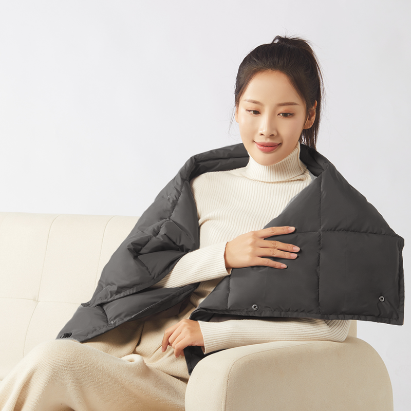 Multifunctional Graphene Heated Down Wrap: woman using the wrap over her shoulders while seated.